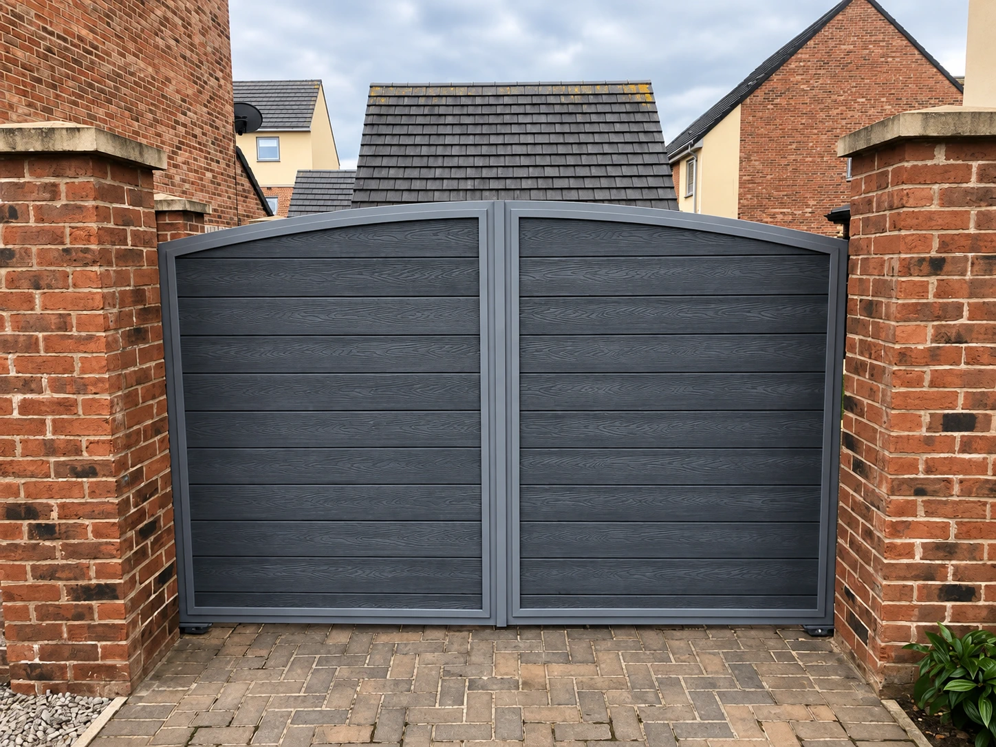 Dark double composite-look driveway gates between brick piers