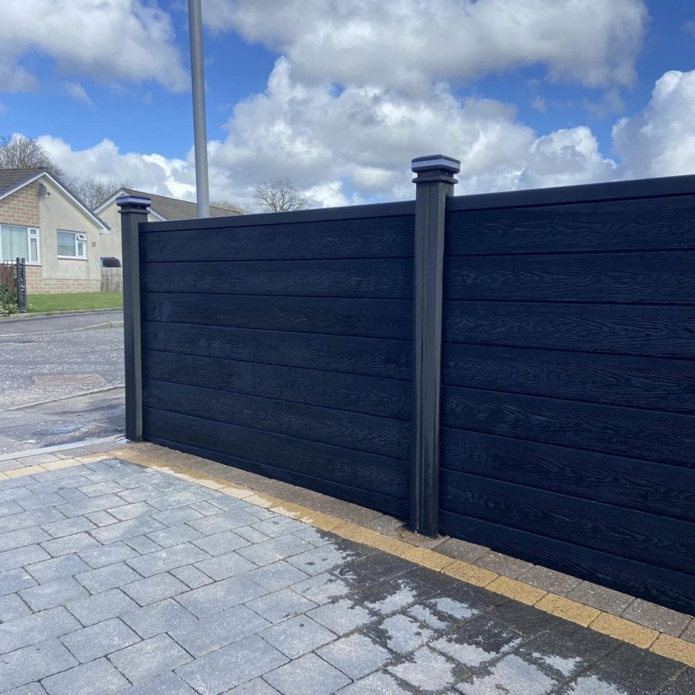 Dark composite privacy fence beside a paved garden