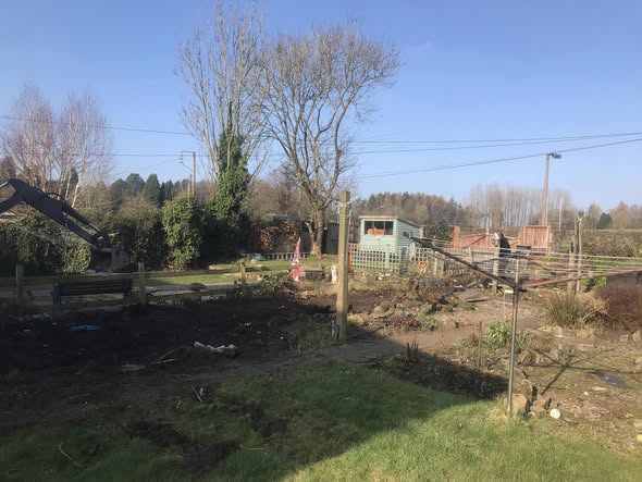 Cheddleton garden during clearance, with open ground, a remaining lawn section and boundary work under way